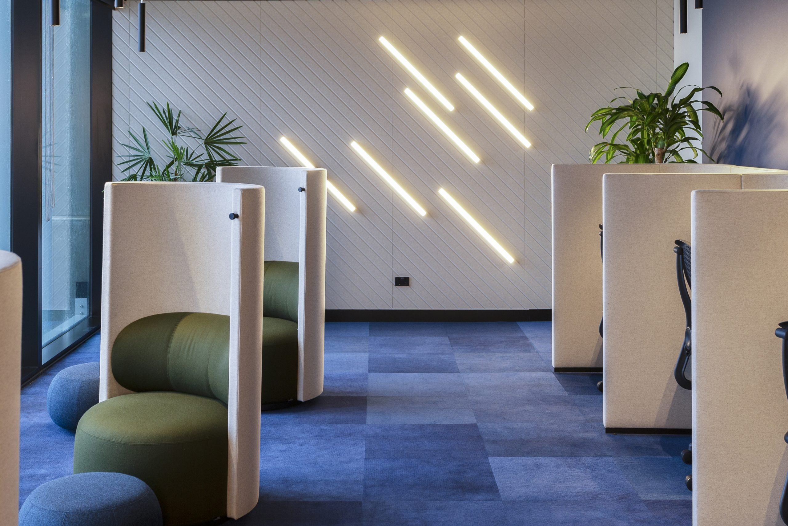 Modern office space with green chairs and white partitions.