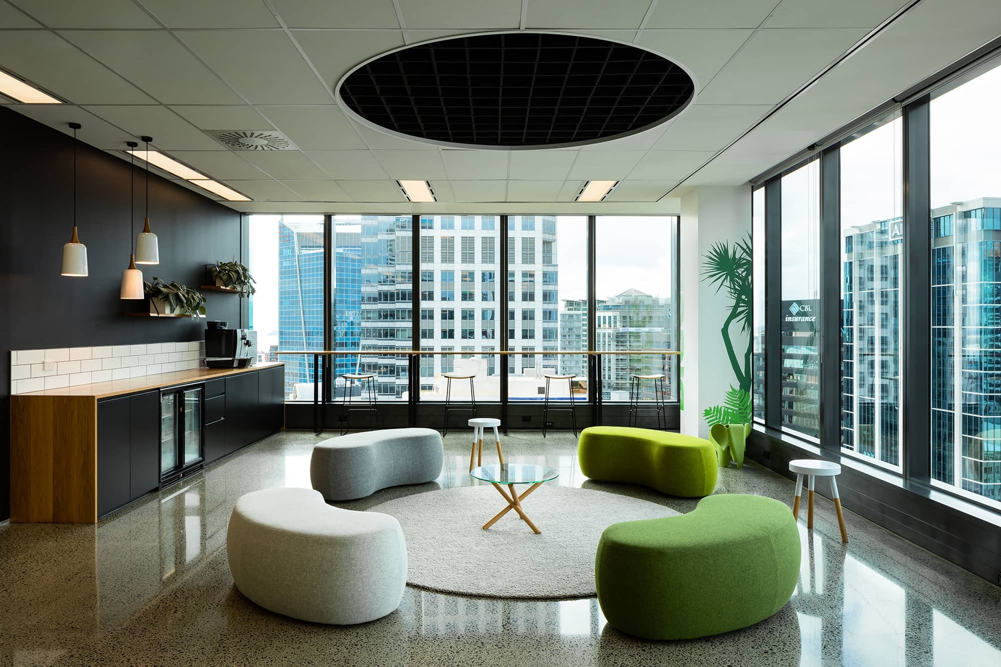 Modern office space with green and gray furniture near large windows with city view